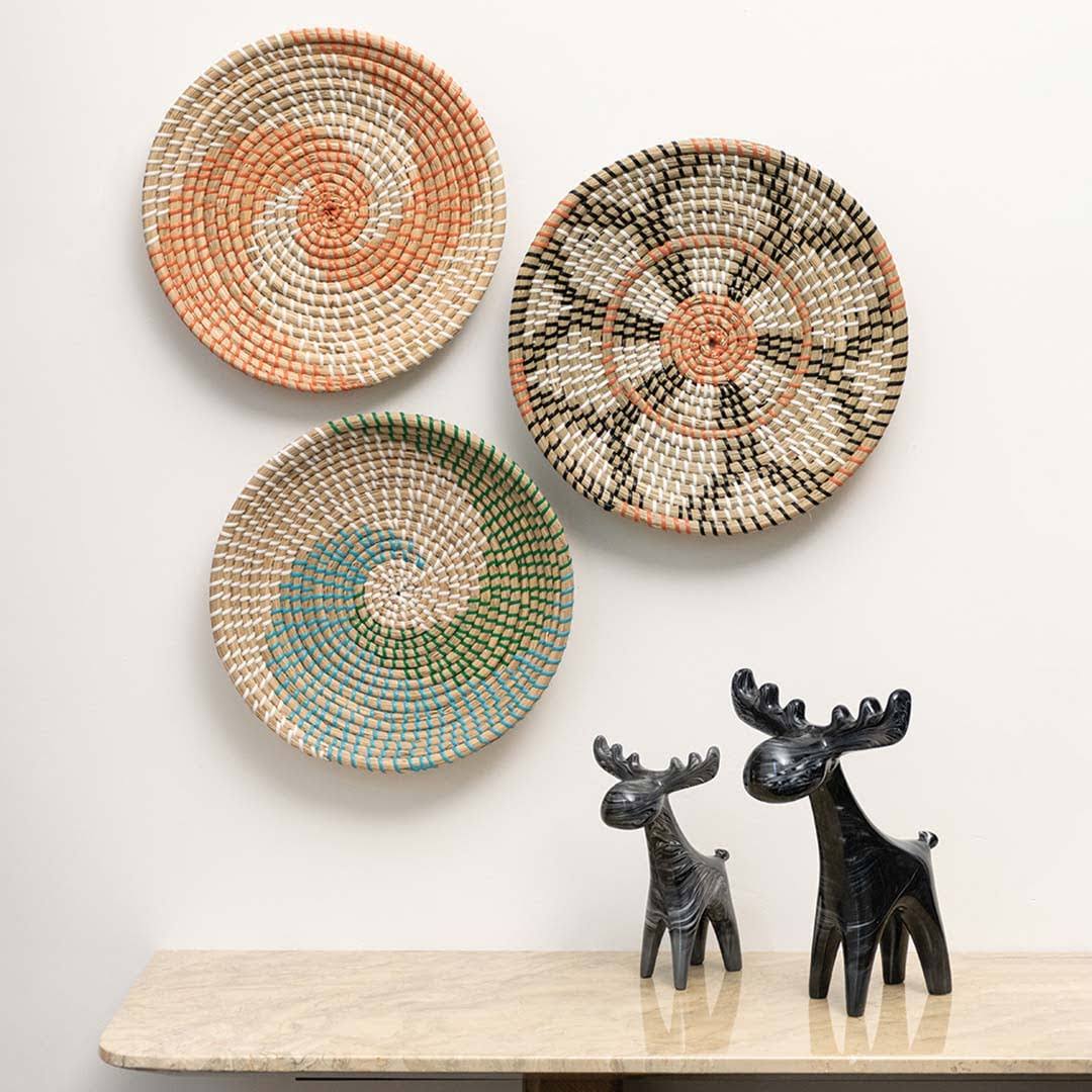 Handcrafted natural seagrass wall basket set with colorful orange and teal swirl patterns in lifestyle living room decor.