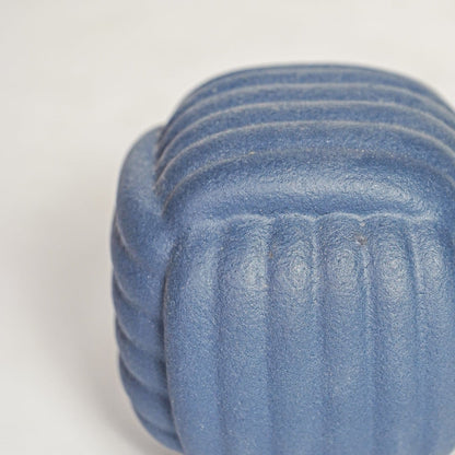Closeup of matte blue ceramic vase with layered ribbed detailing ideal for elegant home decor shelf or side table styling.