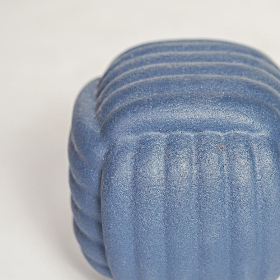 Closeup of matte blue ceramic vase with layered ribbed detailing ideal for elegant home decor shelf or side table styling.