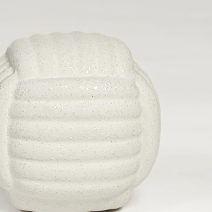 Close view of white ceramic textured decorative jar featuring rounded shape and subtle patterned surface.