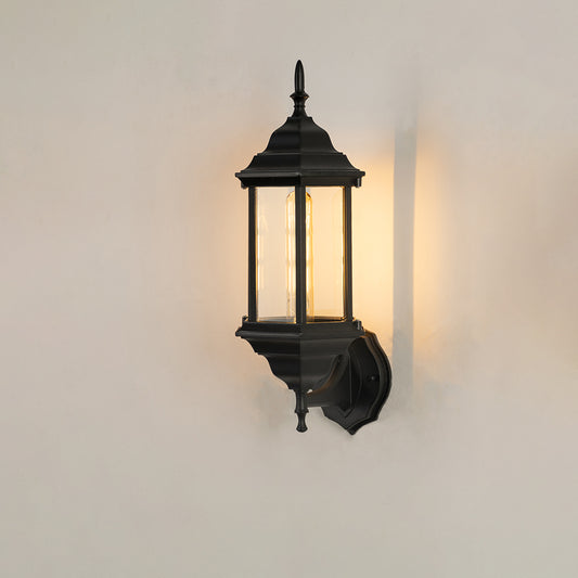 Classic black aluminum outdoor wall lantern on white background with clear elongated paneled glass shade for patio path decor.
