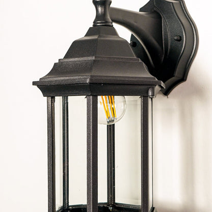Closeup of black metal outdoor wall lantern with clear glass panels for elegant exterior lighting decor styling.