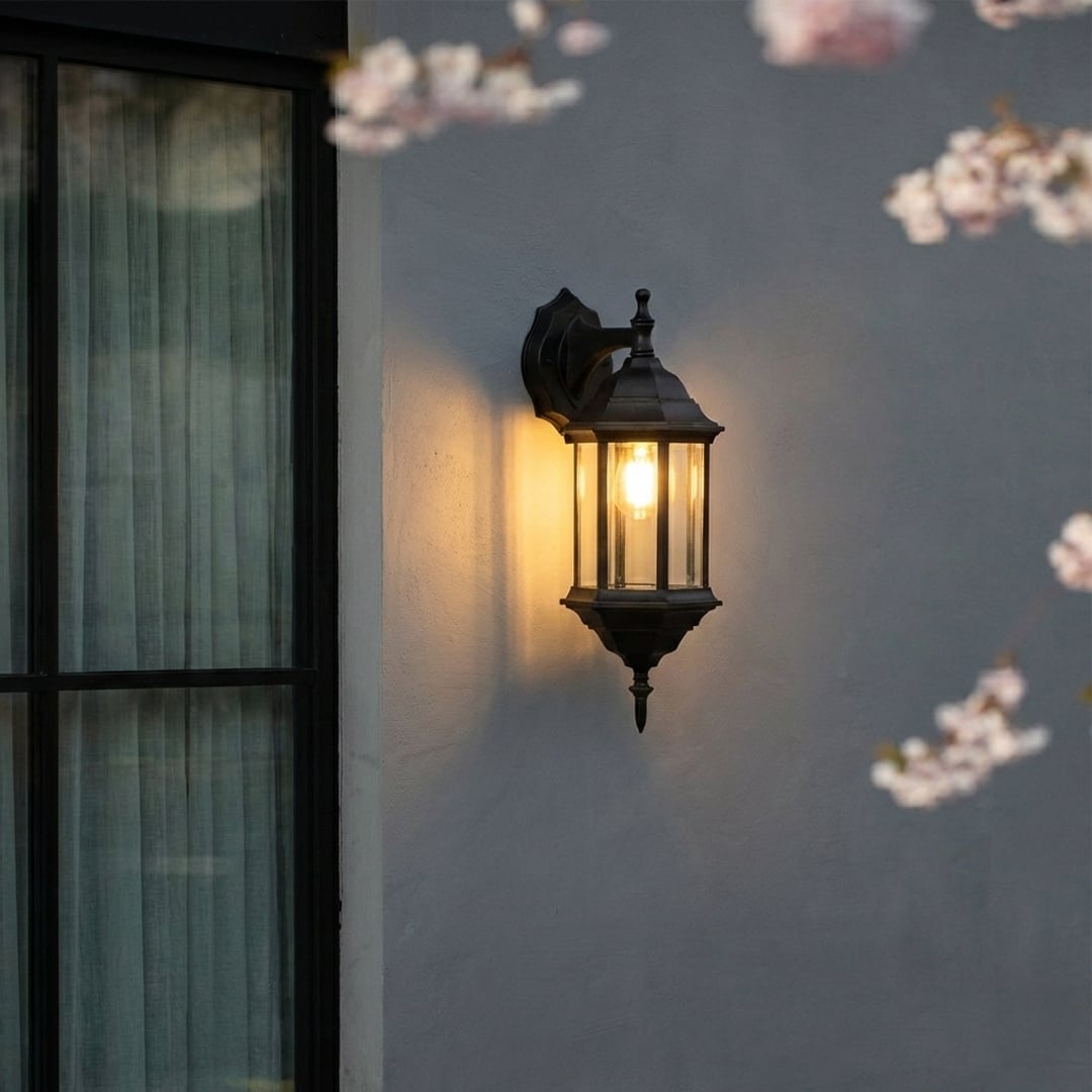 Black metal outdoor wall lantern with warm ambient glow for elegant exterior lighting decor styling ideas.