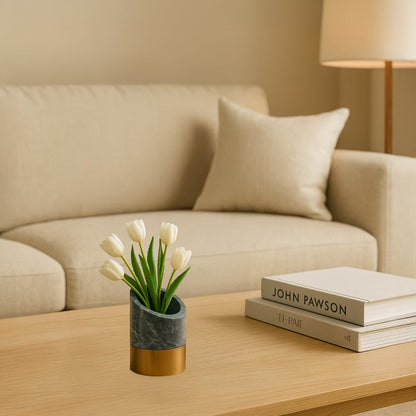 Minimal decorative planter with marble finish and brass base placed on wooden coffee table holding white flowers for modern living room decor.