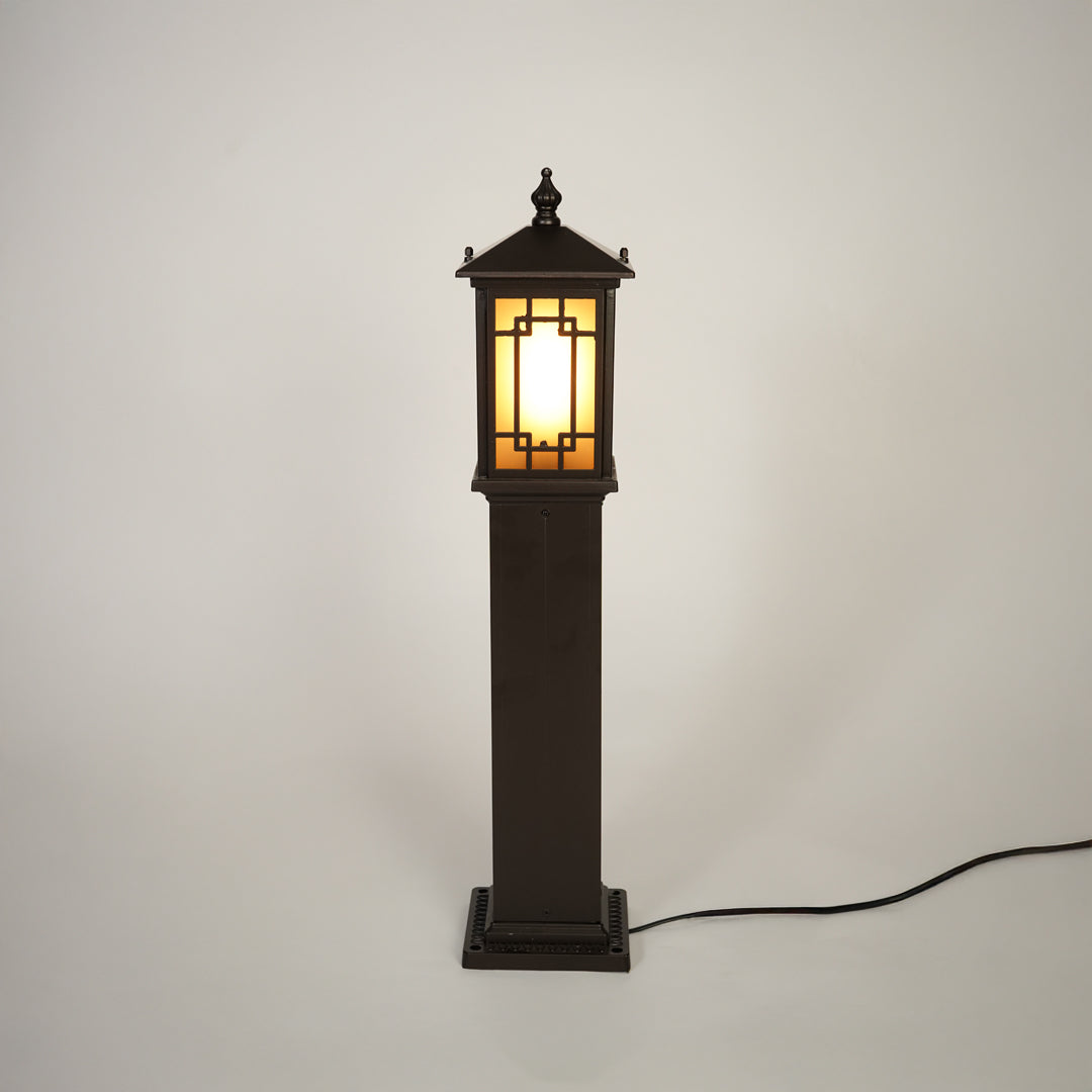 Traditional outdoor bollard light with black metal frame and glass panels on clean background perfect for exterior home lighting.