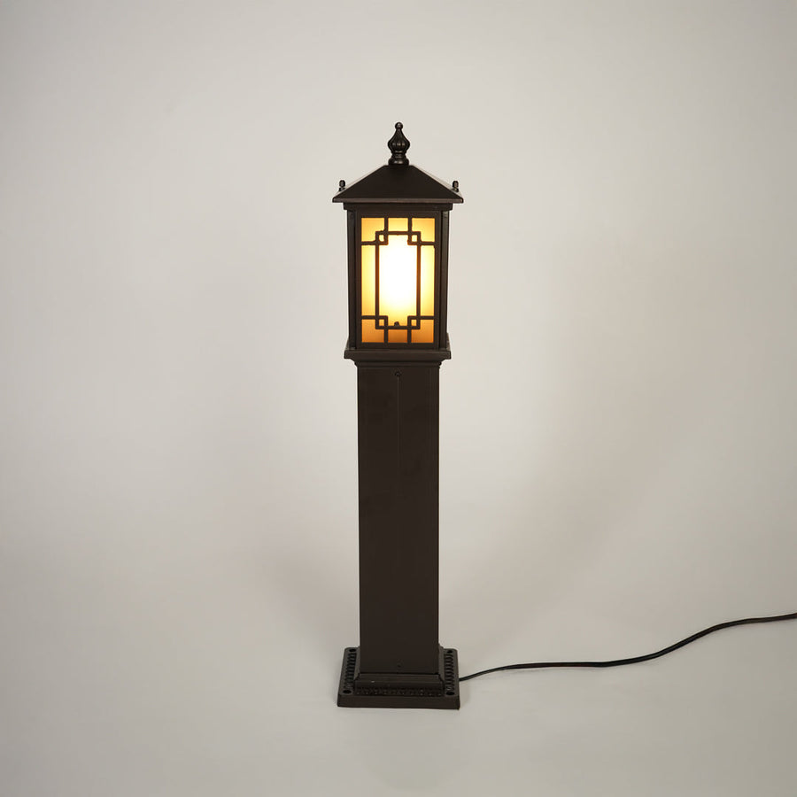 Traditional outdoor bollard light with black metal frame and glass panels on clean background perfect for exterior home lighting.