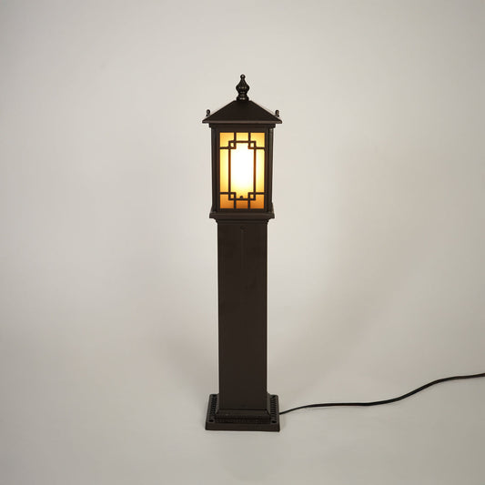 Traditional outdoor bollard light with black metal frame and glass panels on clean background perfect for exterior home lighting.