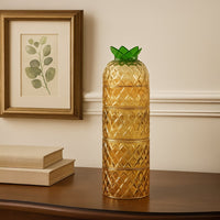 Decorative pineapple shaped yellow glass vase on wooden shelf for unique fun home decor and creative interior styling.