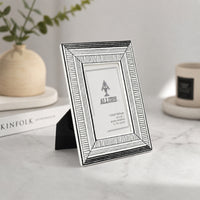Silver metal photo frame placed on marble table for elegant contemporary home decor styling.