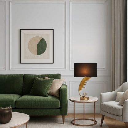 Gold sculpted table lamp with a curved artistic base and black rectangular shade placed on a round side table adding warm ambient lighting to a modern living room.