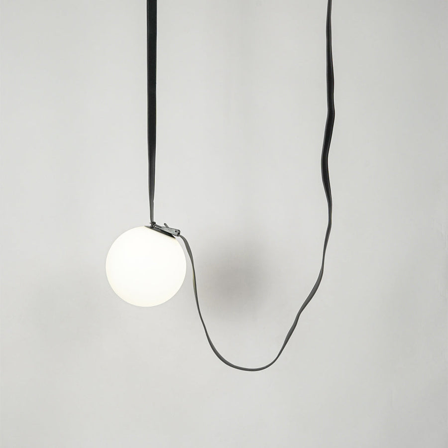 White glass pendant light with black fabric cord designed for stylish modern home decor spaces.