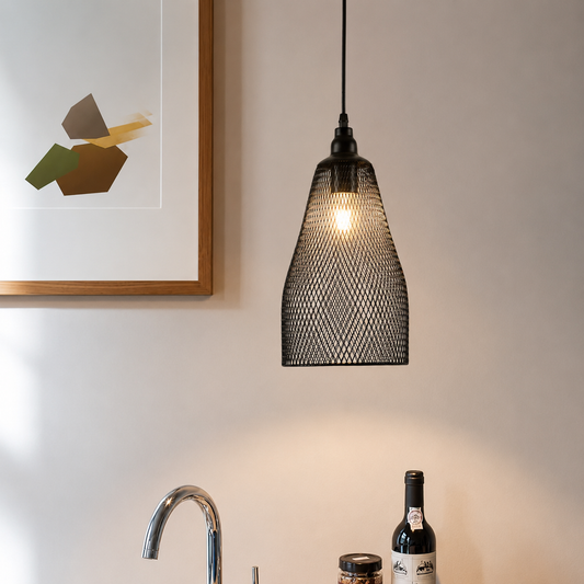 A black metal mesh pendant light hanging in a kitchen above a sink, with a wine bottle and a framed abstract print on the wall.