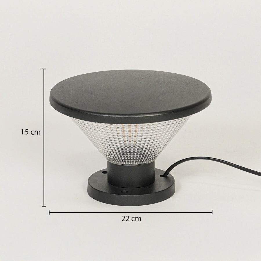 Contemporary outdoor surface light with black metal top and textured glass diffuser on neutral background 15 cm height 22 cm width ideal for garden or pathway lighting.

