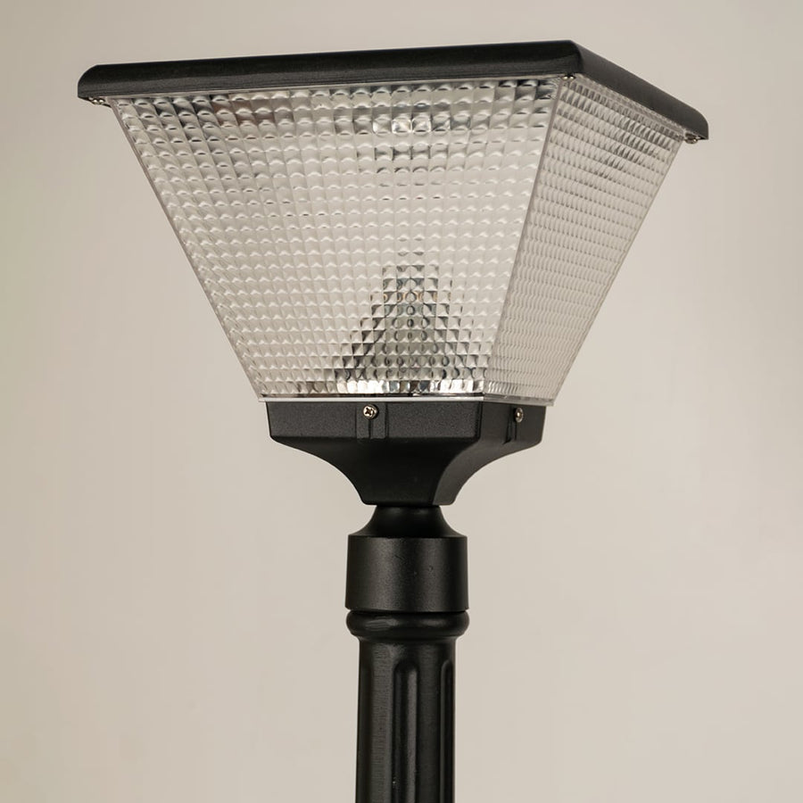 Closeup of black solar outdoor street light with textured glass shade for elegant exterior decor use.