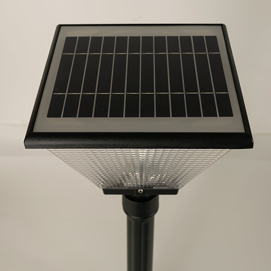 Closeup of black solar outdoor street light with textured glass shade for elegant exterior decor use.