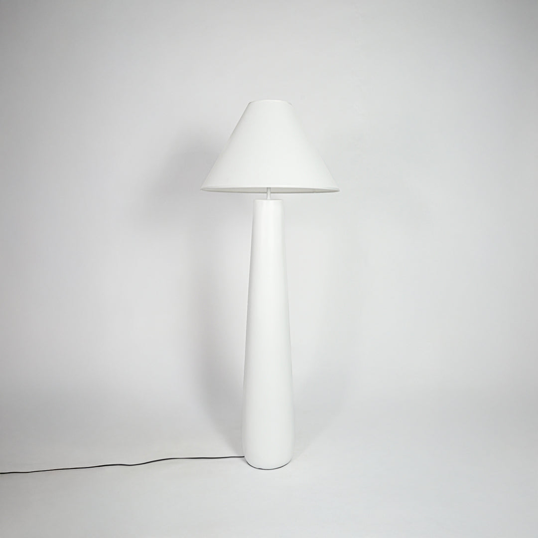 Table lamp with white fabric shade and sleek white base placed on neutral background ideal for modern bedroom or living room decor lighting.