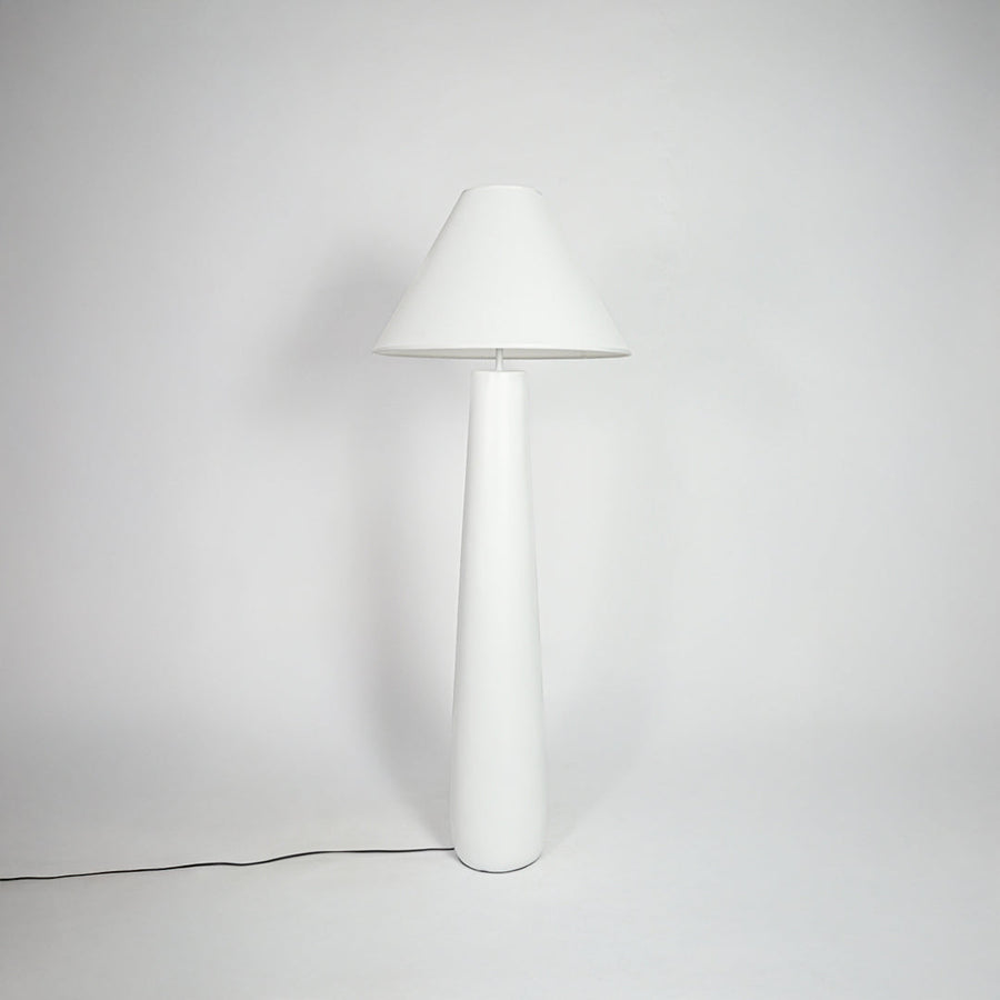 Table lamp with white fabric shade and sleek white base placed on neutral background ideal for modern bedroom or living room decor lighting.