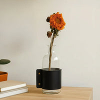 Black ceramic decorative vase styled with an orange flower for modern tabletop decor and elegant interior styling.