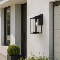 Black metal outdoor wall lantern with clear glass for porch entrance patio and exterior walls with warm ambient lighting.