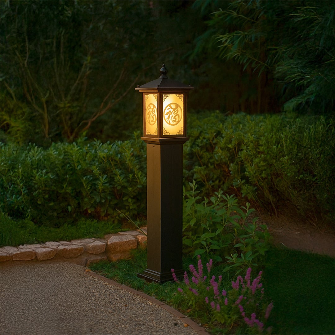 Brown outdoor pillar lamp with glowing decorative Chinese pattern glass lighting a garden pathway at night creating a warm inviting ambience among lush greenery.
