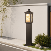 Traditional black iron patterned grid glass pillar post lantern on concrete driveway path for modern house garage walkway.