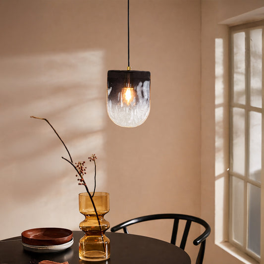 Decorative pendant light with smoky glass shade installed in cozy interior setting creating ambient warm lighting decor appeal.