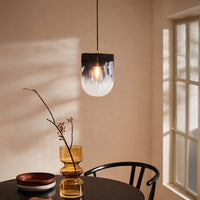 Decorative pendant light with smoky glass shade installed in cozy interior setting creating ambient warm lighting decor appeal.