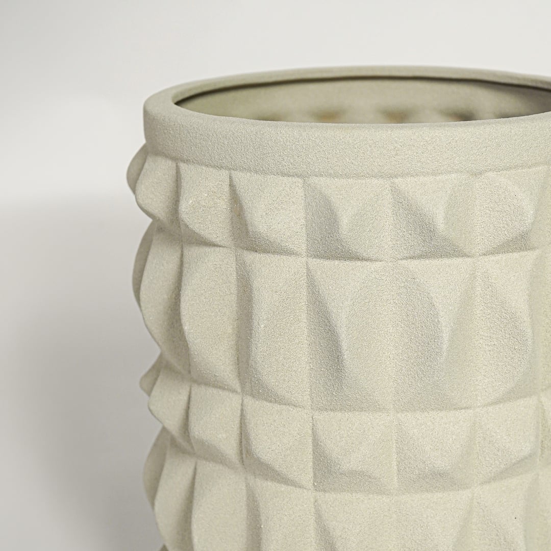 Close view of light beige ceramic planter highlighting geometric texture matte finish and cylindrical modern shape.