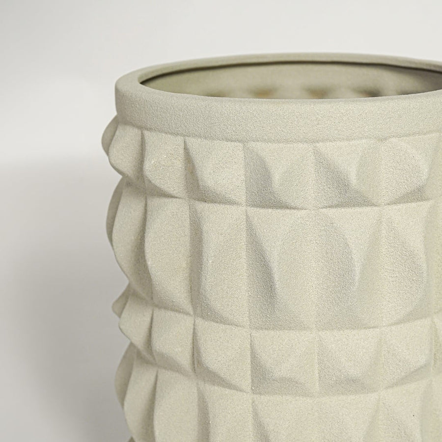 Close view of light beige ceramic planter highlighting geometric texture matte finish and cylindrical modern shape.