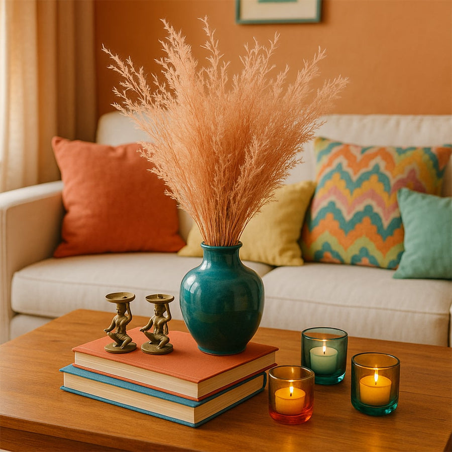 Peach dried grass stems arranged in a teal ceramic vase styled on a wooden coffee table creating warm cozy home decor accents in a modern living room.