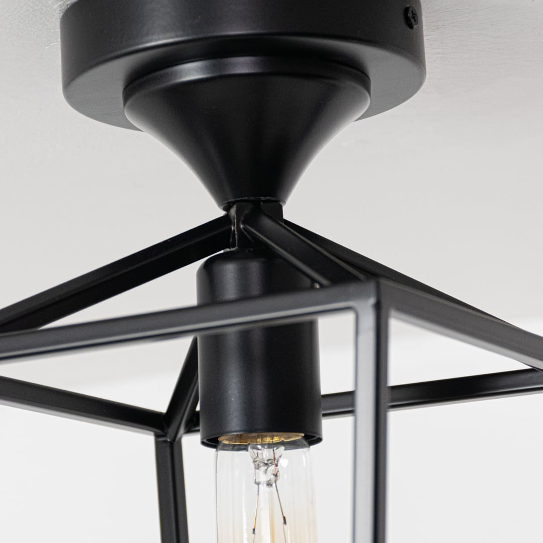 Closeup of black outdoor ceiling lantern highlighting the warm glowing bulb and clear glass cylinder designed for stylish exterior lighting.