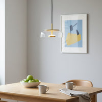 Clear glass and brass metal pendant light creating warm ambience above the dining table indoors.
