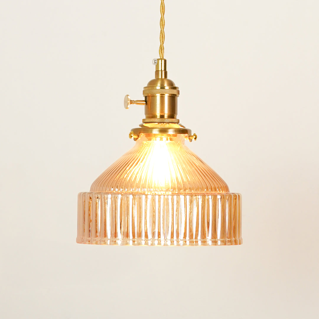 Amber ribbed glass pendant light with gold metal fixture illuminated to showcase elegant decorative ceiling lighting.