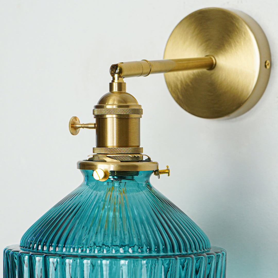 Closeup of gold metal wall light with blue ribbed glass shade showcasing intricate detailing and premium finish for modern decor styling.