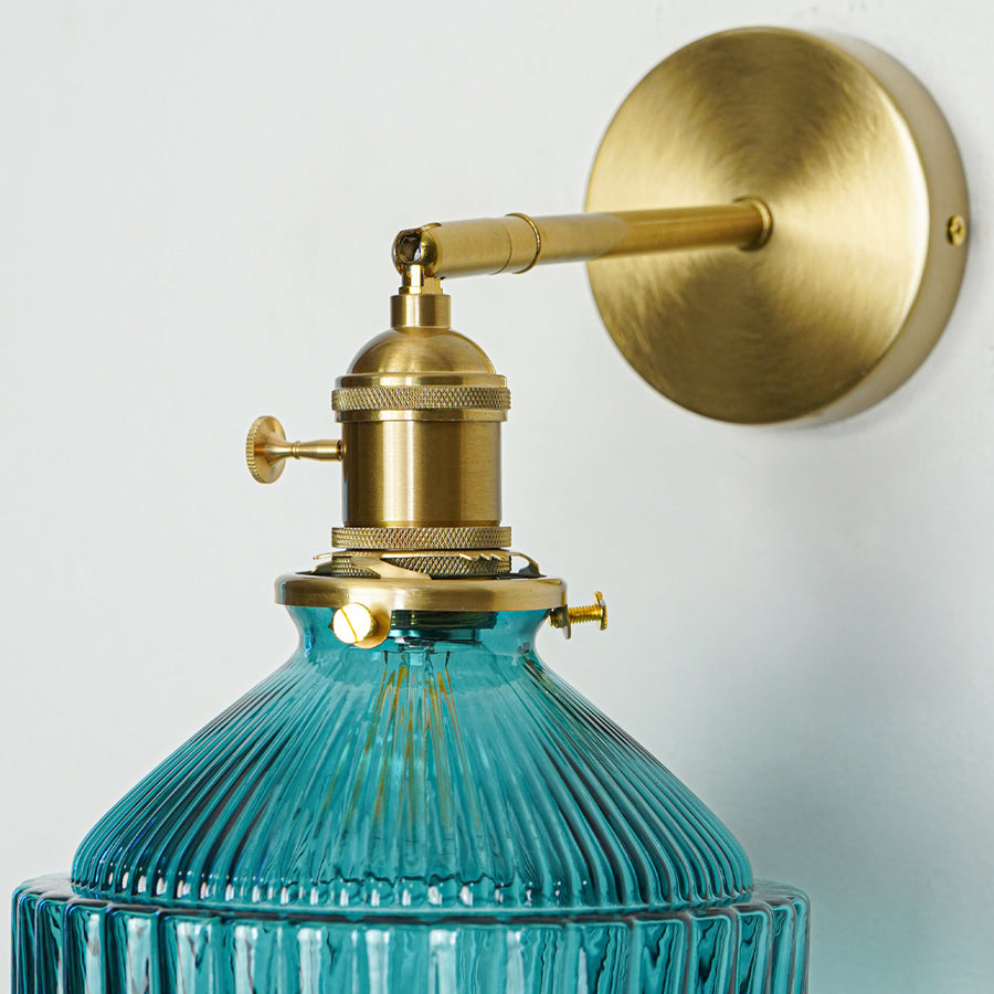 Closeup of gold metal wall light with blue ribbed glass shade showcasing intricate detailing and premium finish for modern decor styling.