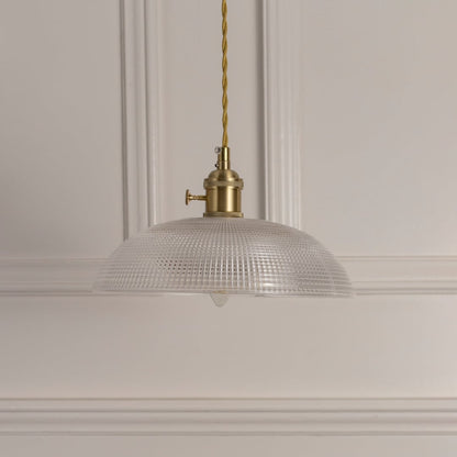 Closeup of clear ribbed glass pendant light with gold metal detailing showcasing refined craftsmanship.