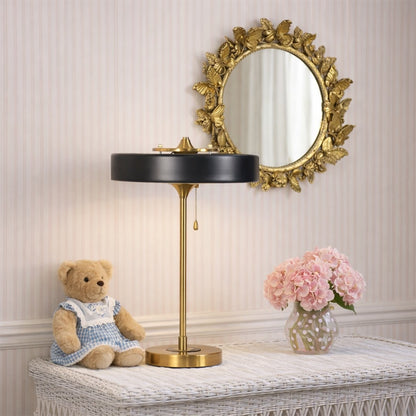 Black and gold metal table lamp with circular shade displayed on a bedside table creating elegant modern ambient lighting.