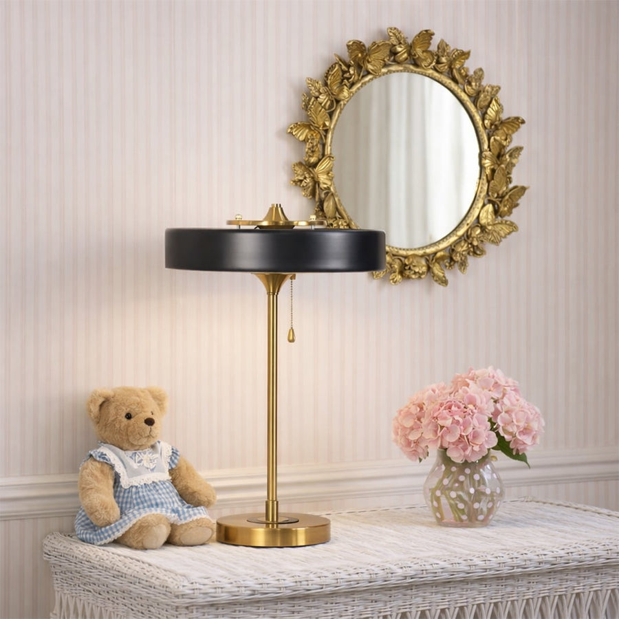 Black and gold metal table lamp with circular shade displayed on a bedside table creating elegant modern ambient lighting.