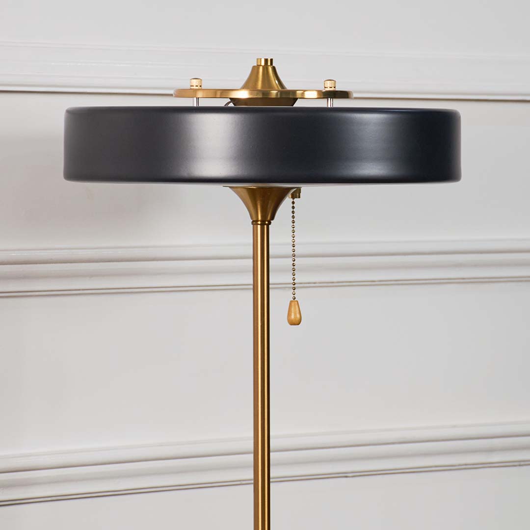 Closeup of modern black and gold table lamp showing round metal shade with sleek detailing and golden accents.