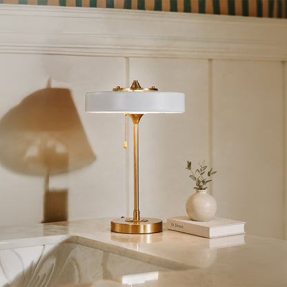 White glass table lamp with brass metal base placed on a side table creating elegant contemporary ambient lighting.