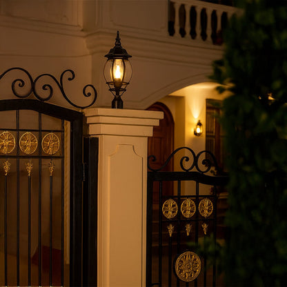Elegant black outdoor pillar lamp glowing warmly on villa gate pillar adding classic style and security to entrance decor.