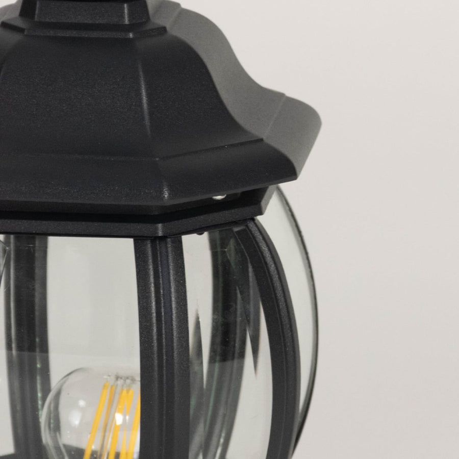 Closeup of decorative black outdoor pillar lamp featuring rounded glass shade and LED bulb with elegant vintage style.