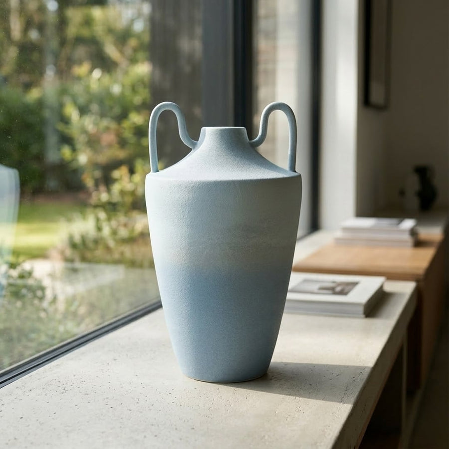 Light blue ceramic decorative flower vase placed near window modern aesthetic home decor styling idea.