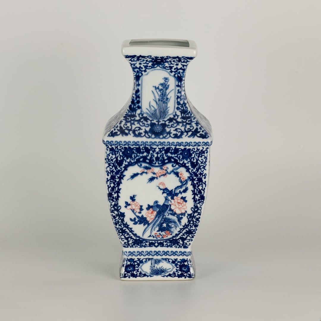 Blue and white ceramic jar with tall angular sides and detailed scenic panels shown on a plain surface creating a refined artistic accent suited for traditional home decor.