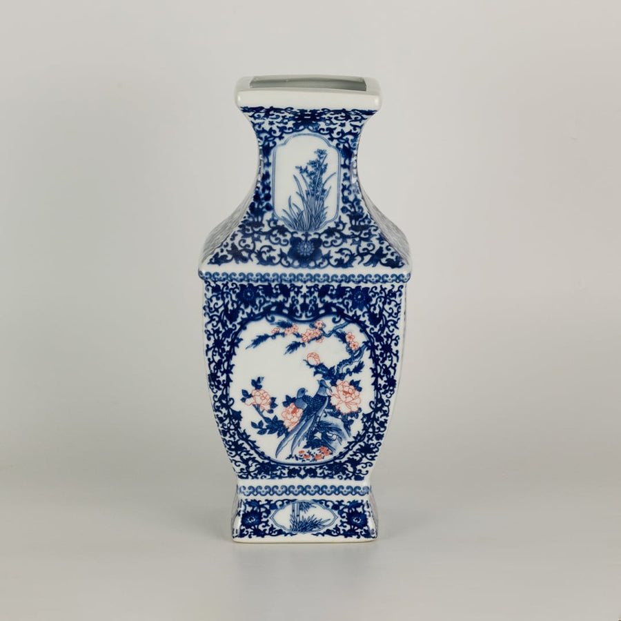 Blue and white ceramic jar with tall angular sides and detailed scenic panels shown on a plain surface creating a refined artistic accent suited for traditional home decor.