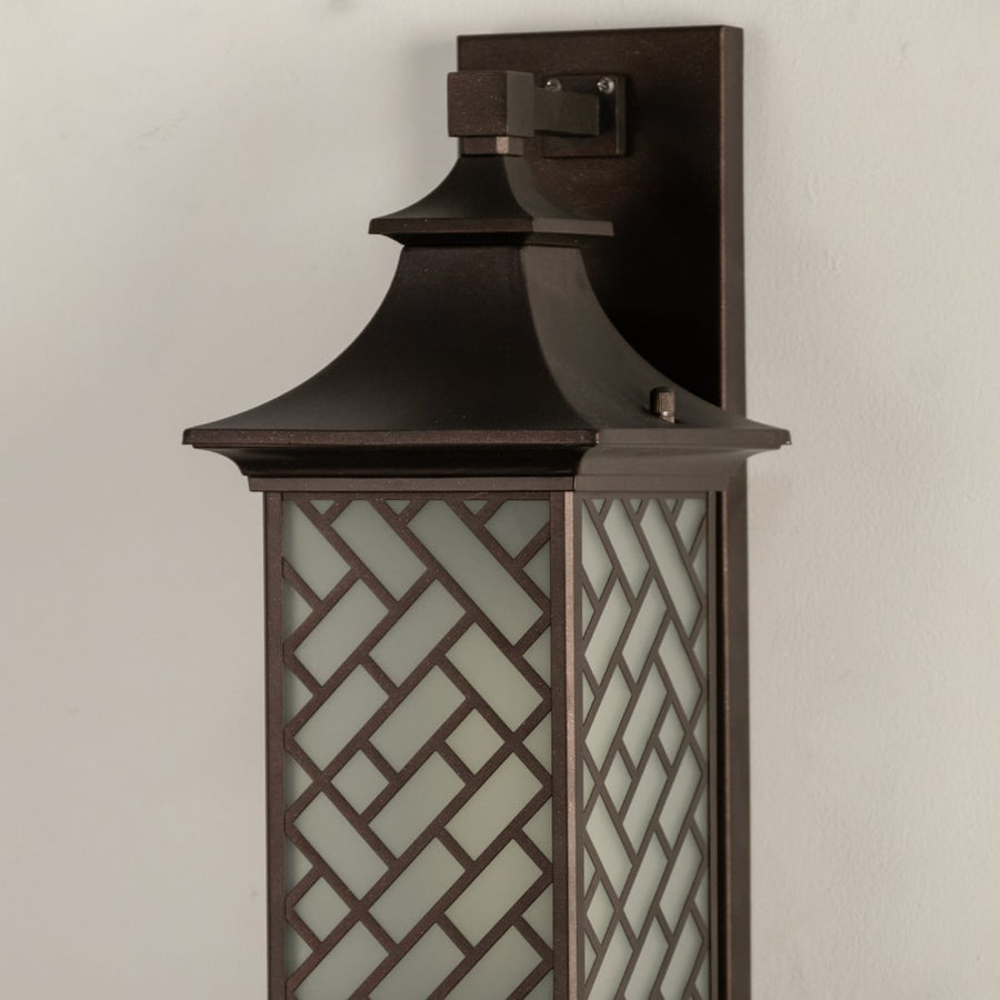 Modern bronze outdoor column wall light closeup image showing textured metallic cap and detailed geometric basketweave frame.