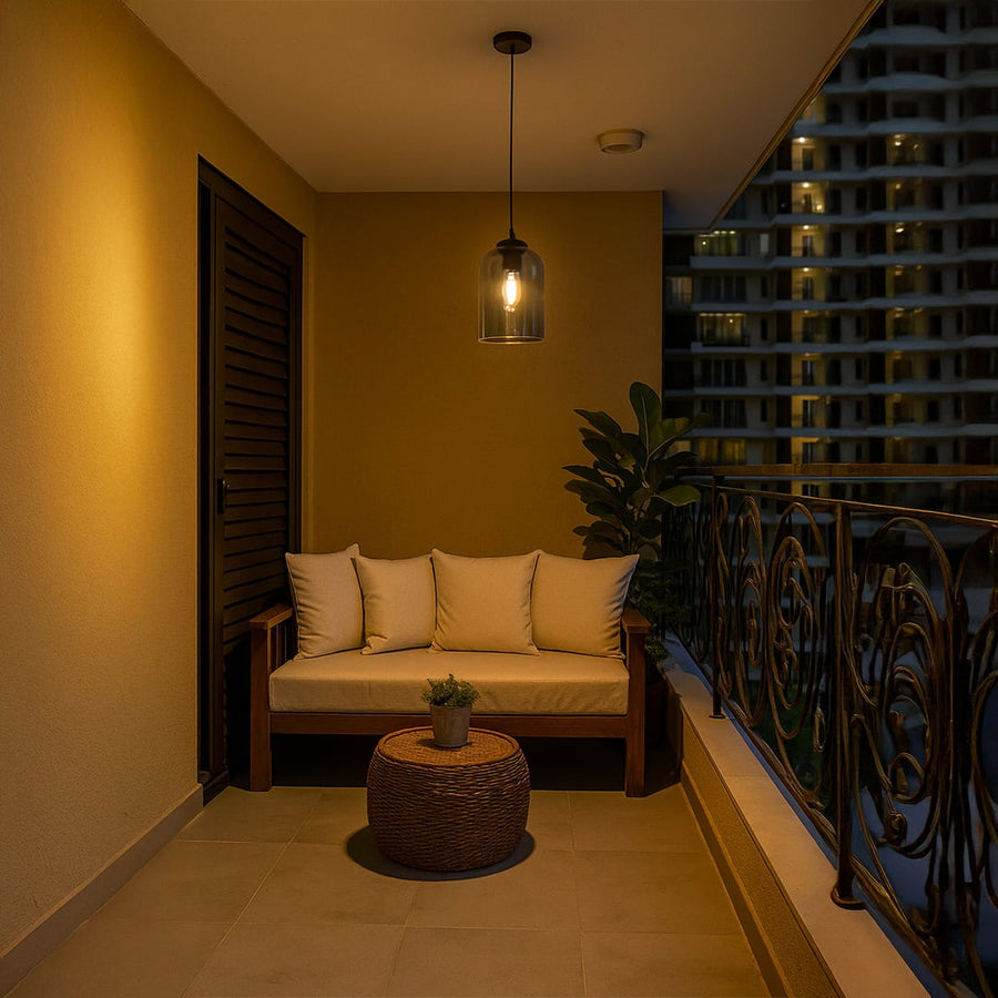 A smoked glass dome pendant light glowing warmly above a cozy balcony seating area creating soft ambient lighting for modern outdoor home decor.