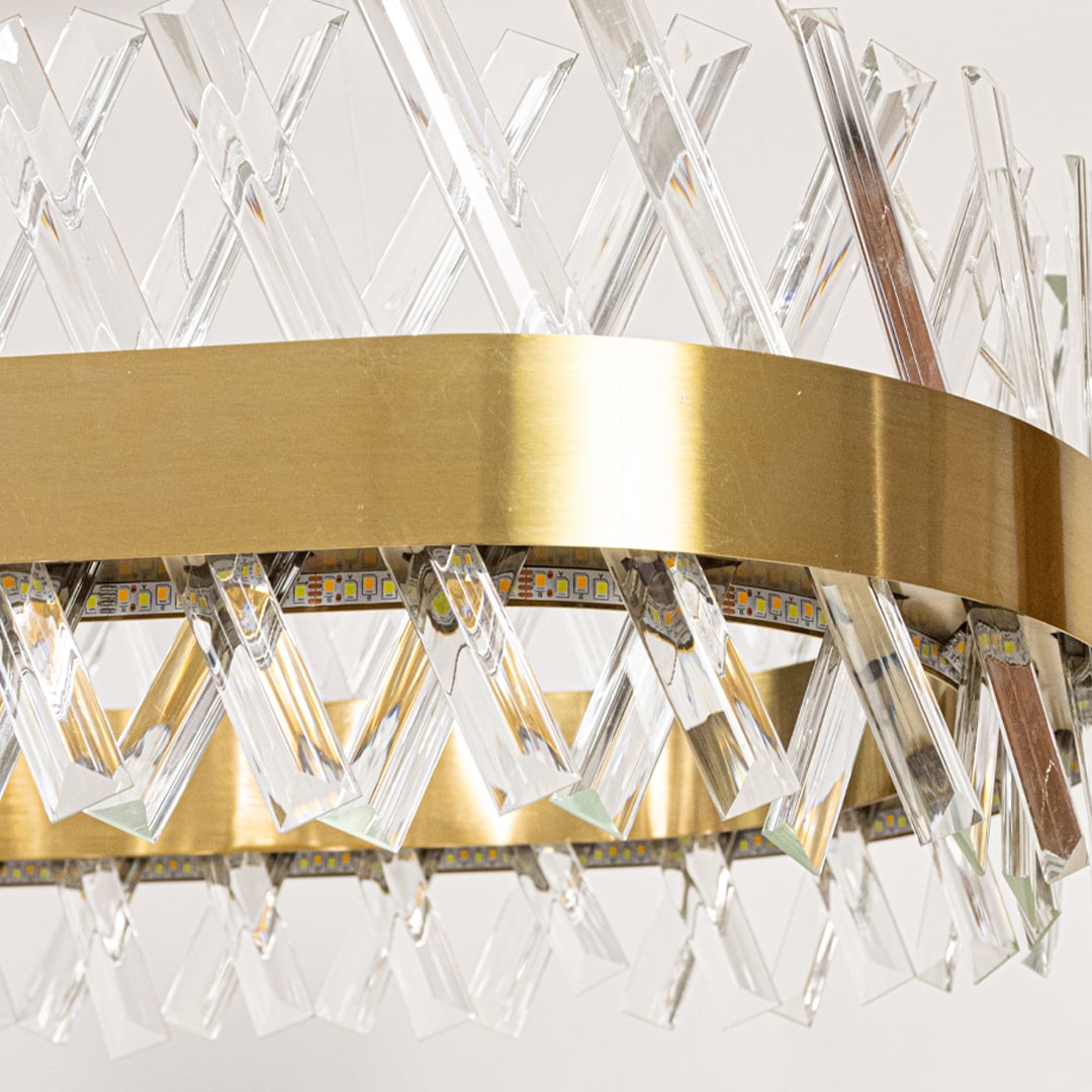 Closeup of gold metal chandelier highlighting the detailed crystal rods and polished metal band designed for elegant luxurious interior lighting.