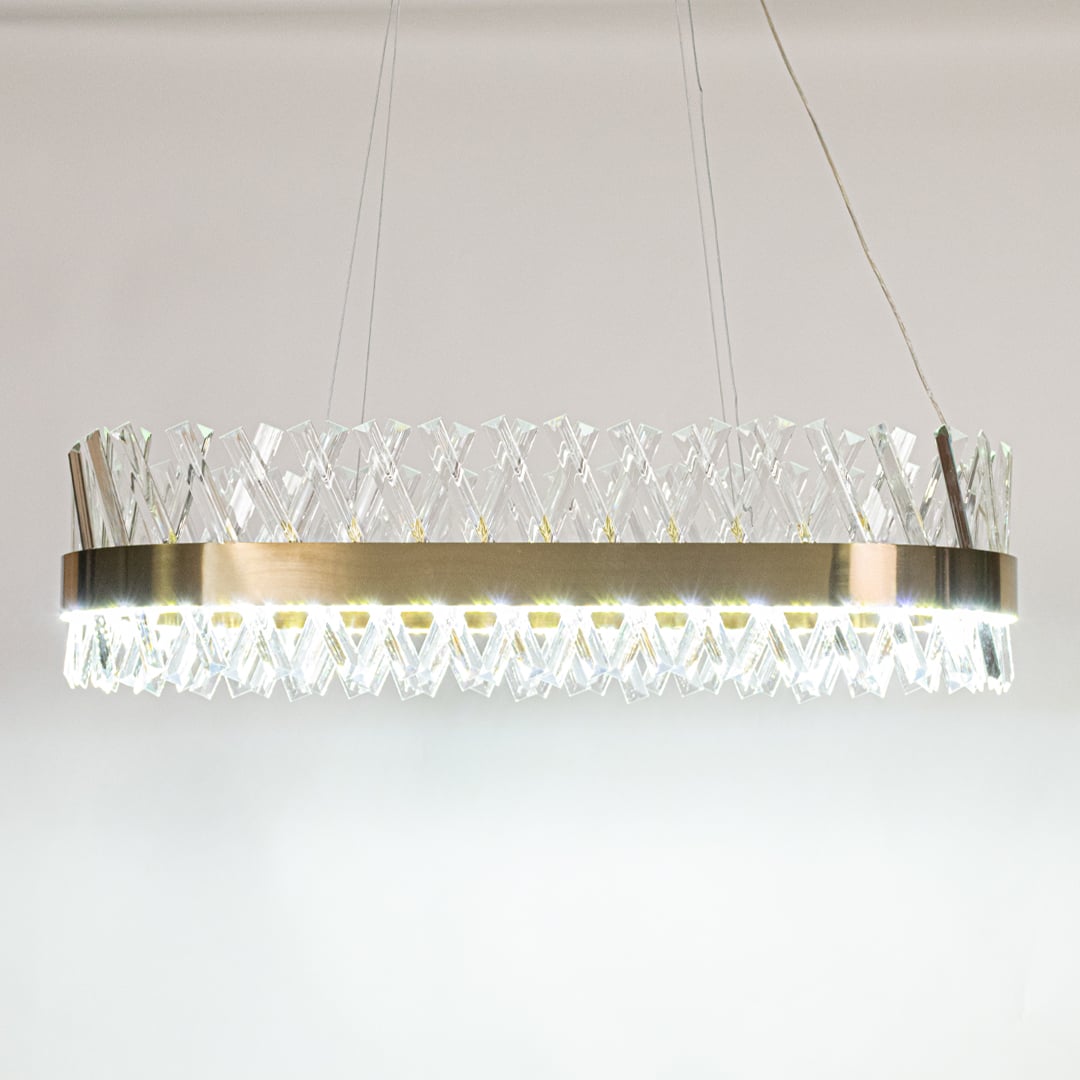 Gold metal chandelier with crystal rods shown with lights on against white background creating a bright luxurious and refined glow for modern interiors.