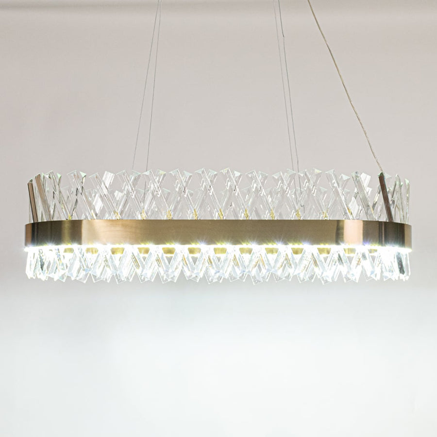 Gold metal chandelier with crystal rods shown with lights on against white background creating a bright luxurious and refined glow for modern interiors.